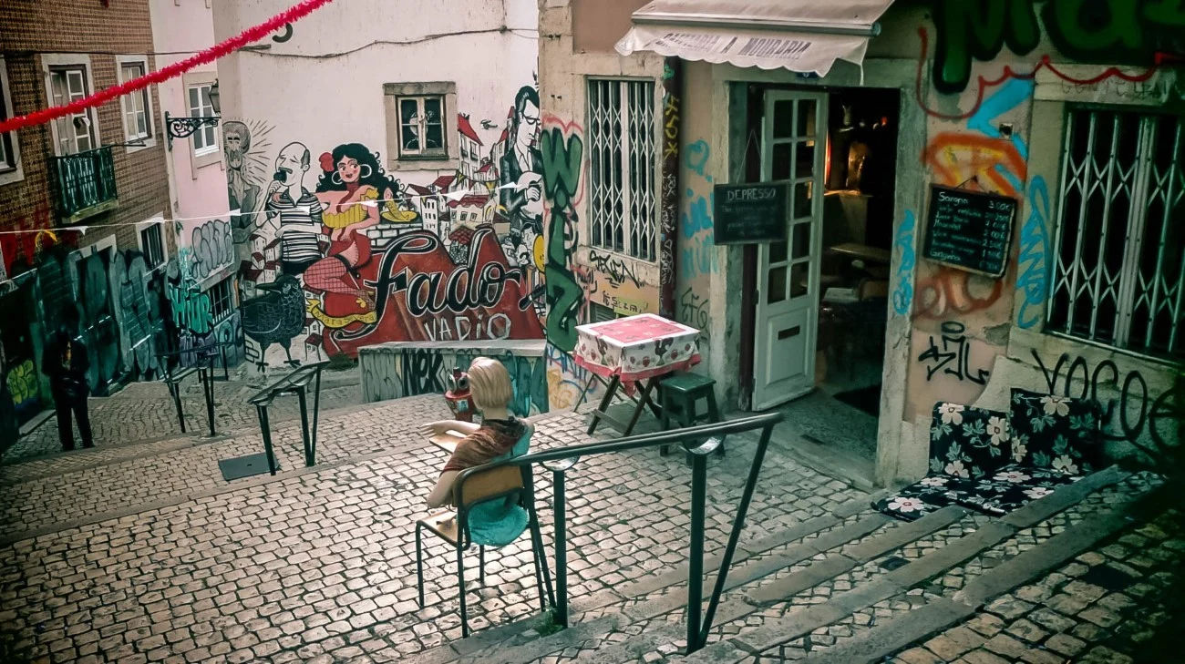 A Fado bar with colorful street murals on a cobblestone alley