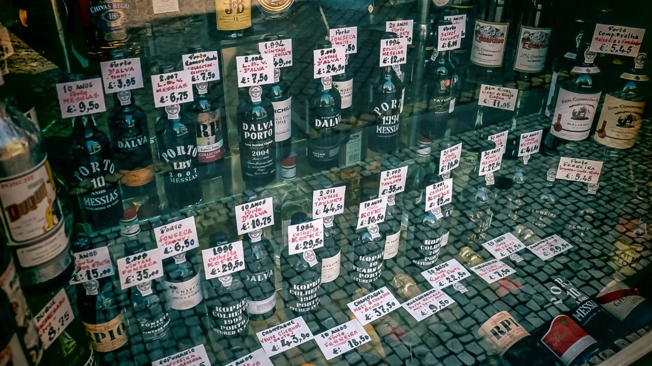 A shop window display of Port wine bottles with handwritten price tags