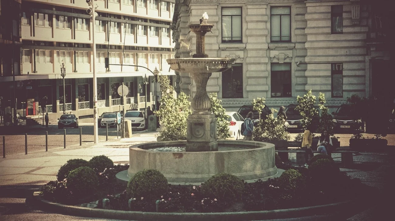 A stone fountain surrounded by classic Porto architecture