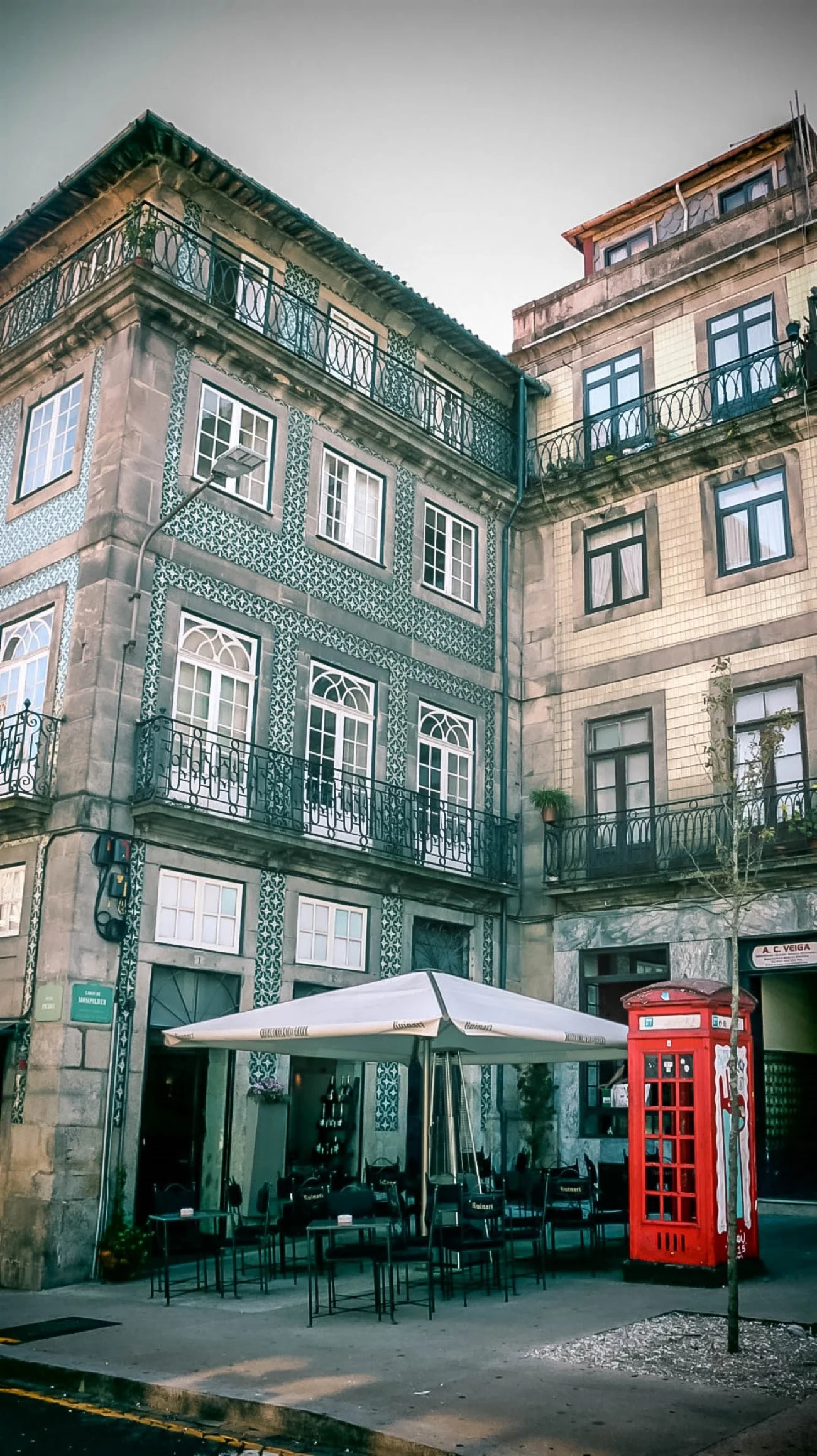 A tiled building with wrought-iron balconies and a red British-style phone booth