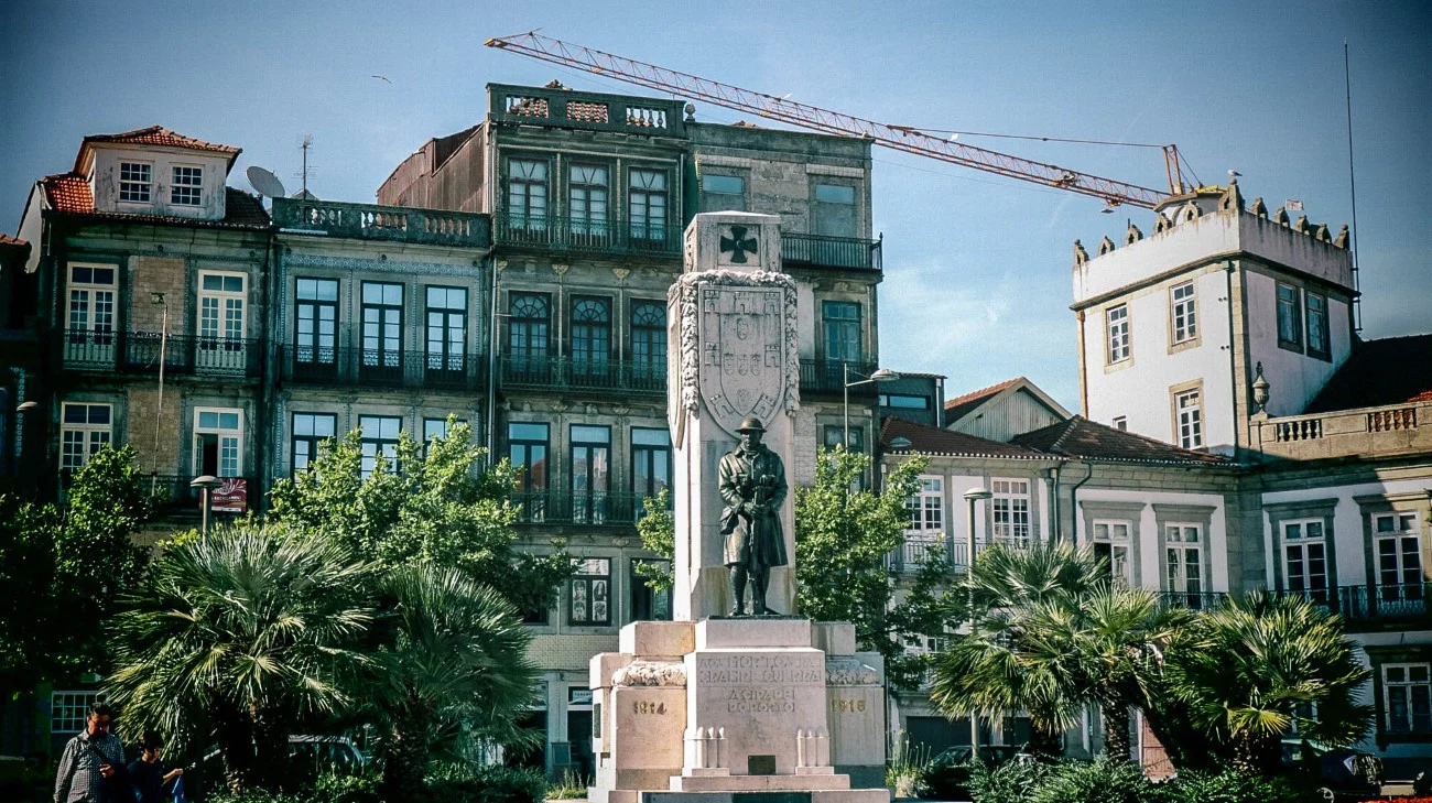 A war memorial statue in a small plaza surrounded by traditional buildings
