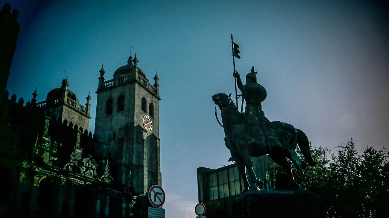 The equestrian statue of Vímara Peres silhouetted against the evening sky with the Sé Cathedral behind