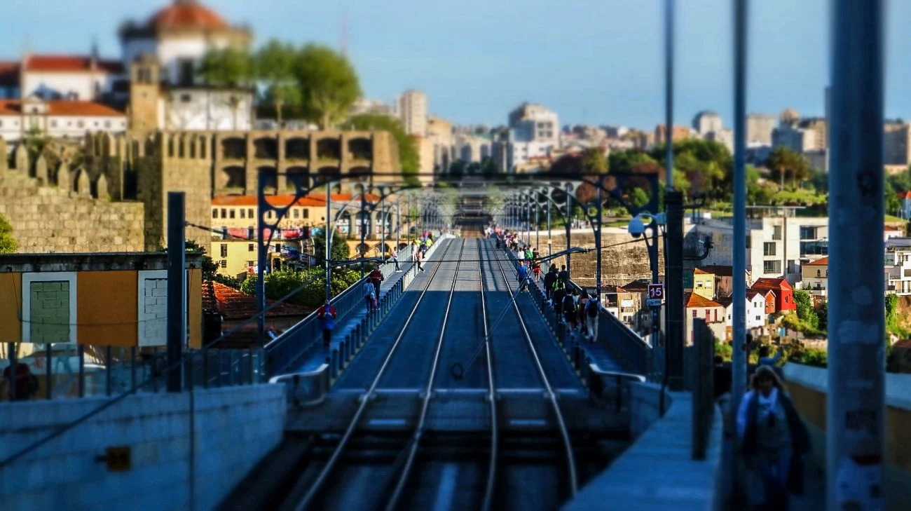 Tilt-shift view looking down the Ponte Luís I bridge with metro tracks and pedestrians