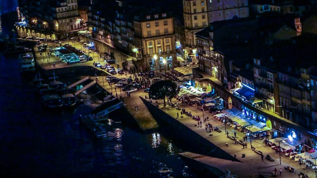 The Ribeira district lit up at night from above, with people gathering along the waterfront