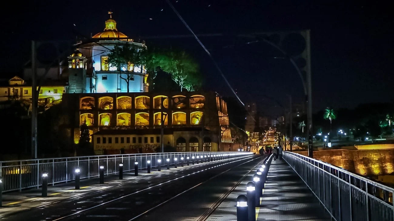 Crossing the Ponte Luís I bridge at night with the Mosteiro da Serra do Pilar illuminated ahead