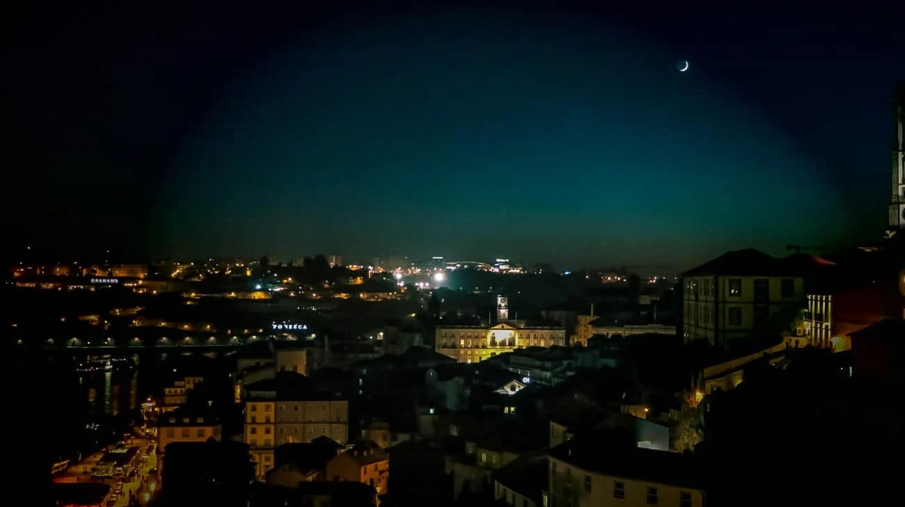 Porto’s night skyline with a crescent moon and Port wine cellar signs glowing across the river