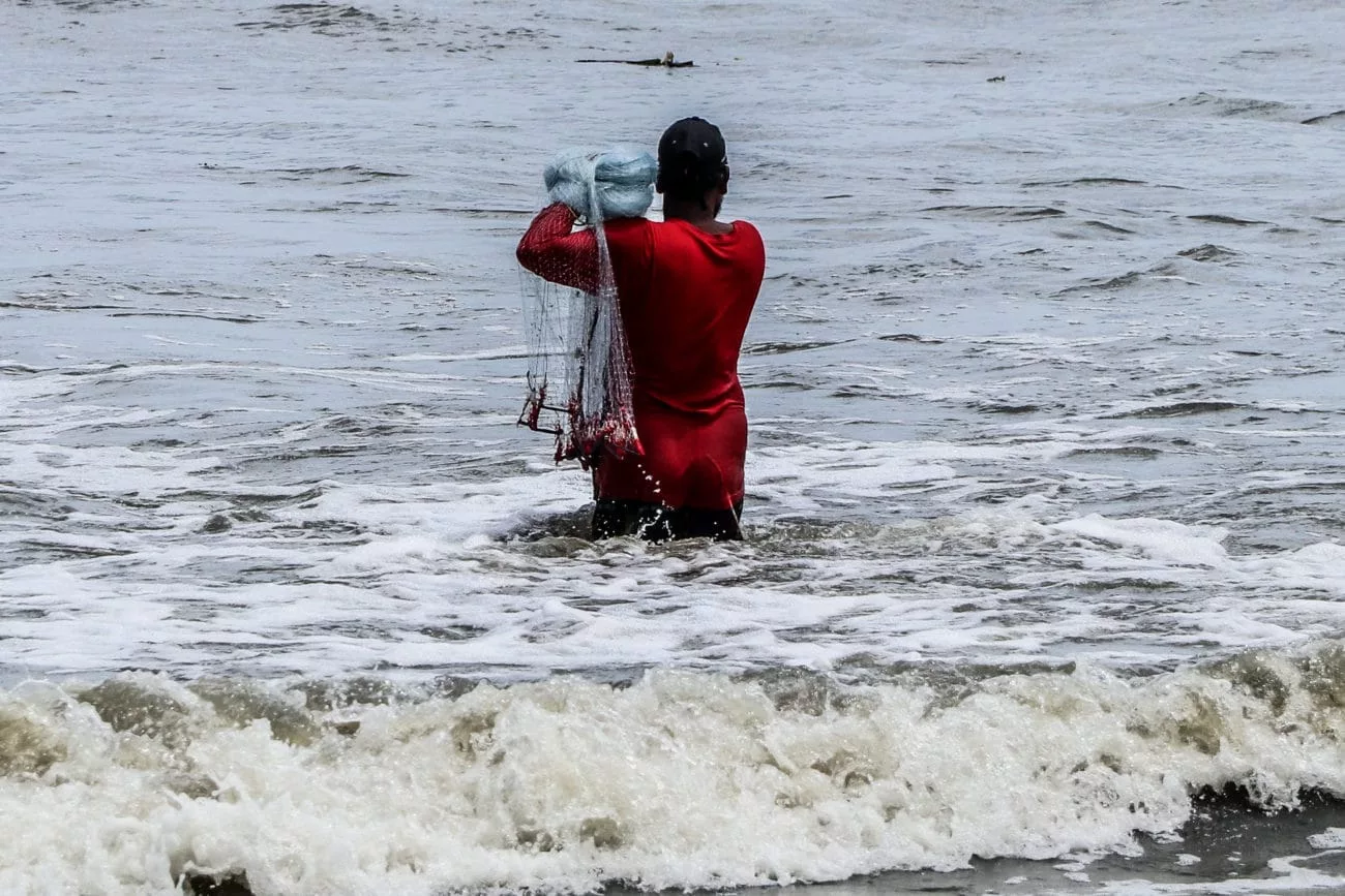 Ein Mann geht ins Meer, um in Fort Kochi Fische zu fangen