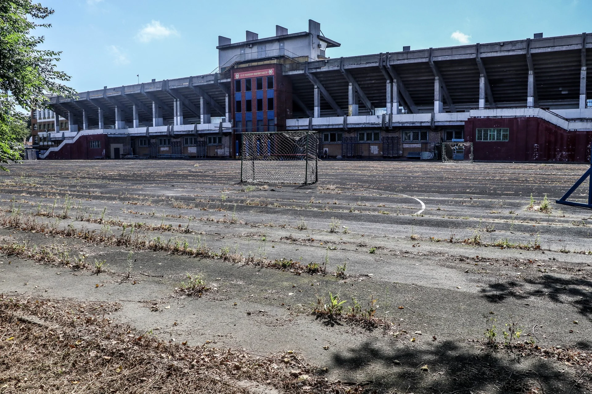 An abandoned Soviet-era stadium with weeds growing through the pitch