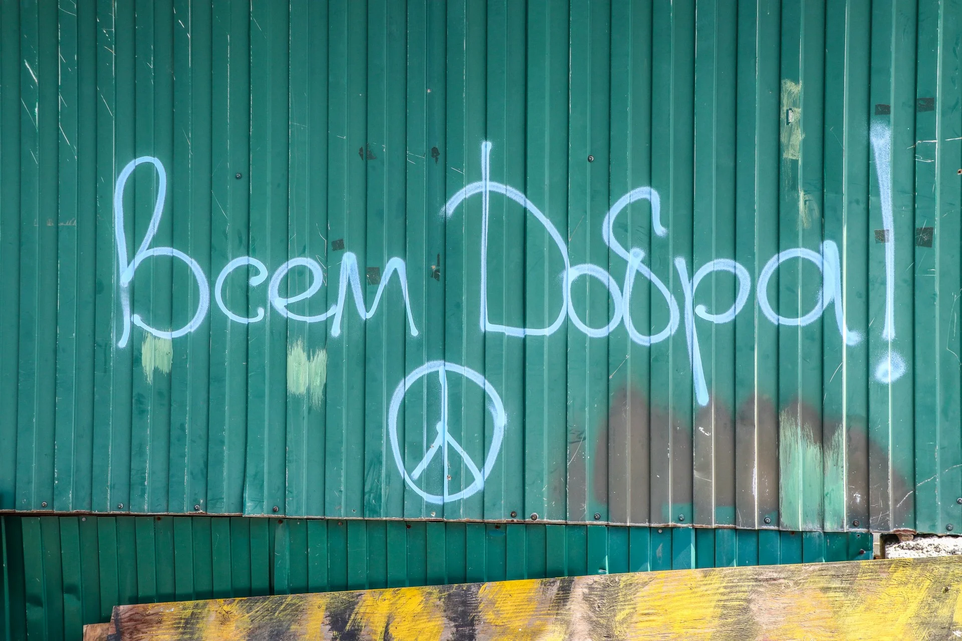 Street graffiti reading ‘Goodness to all’ with a peace sign