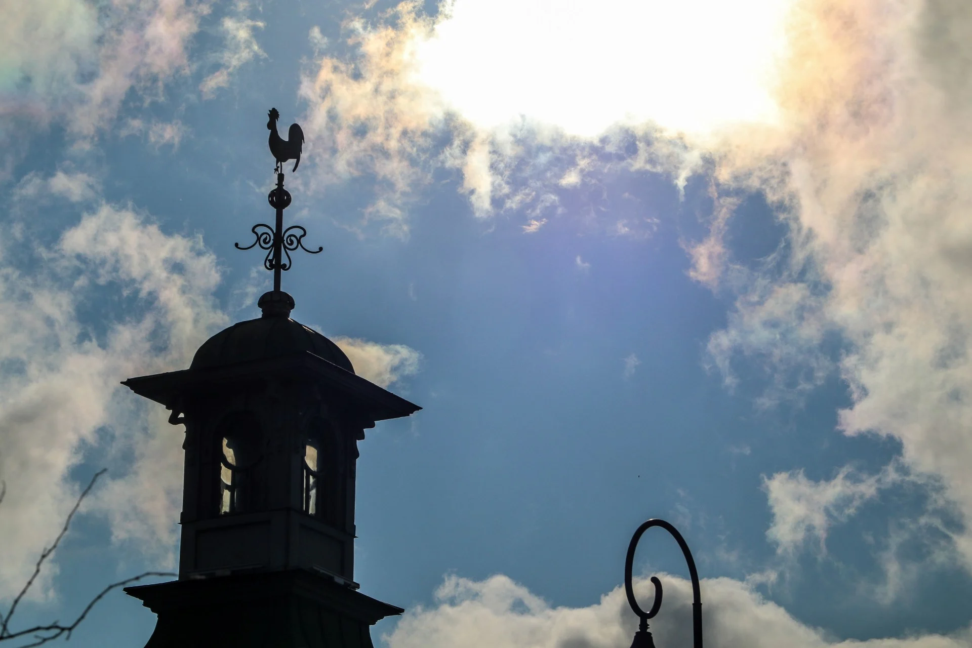 A weathervane rooster silhouetted on top of an old cupola