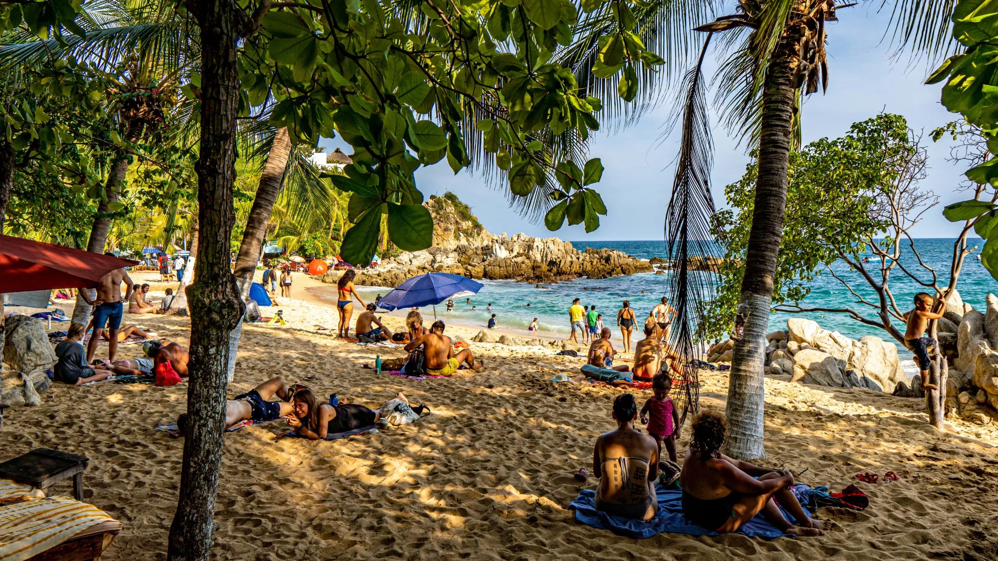 Tourists enjoy the shade, sunshine, and beach in Puerto Escondido