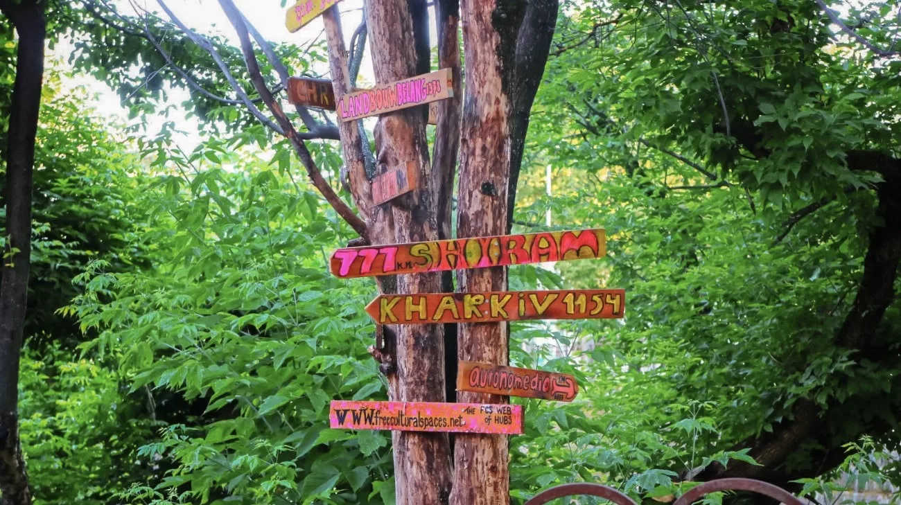 Handmade wooden signs pointing to faraway cities on a tree in Uzupis