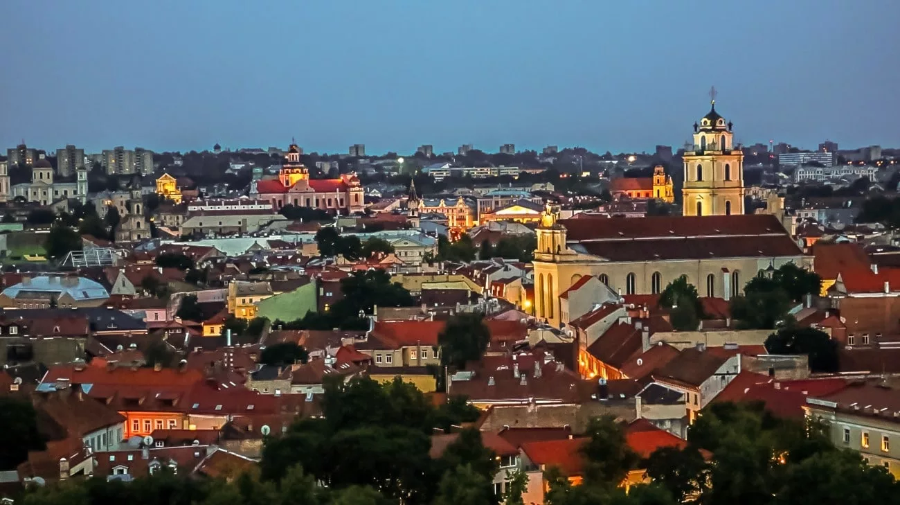Blue-hour panorama of Old Town, church towers glowing above the rooftops
