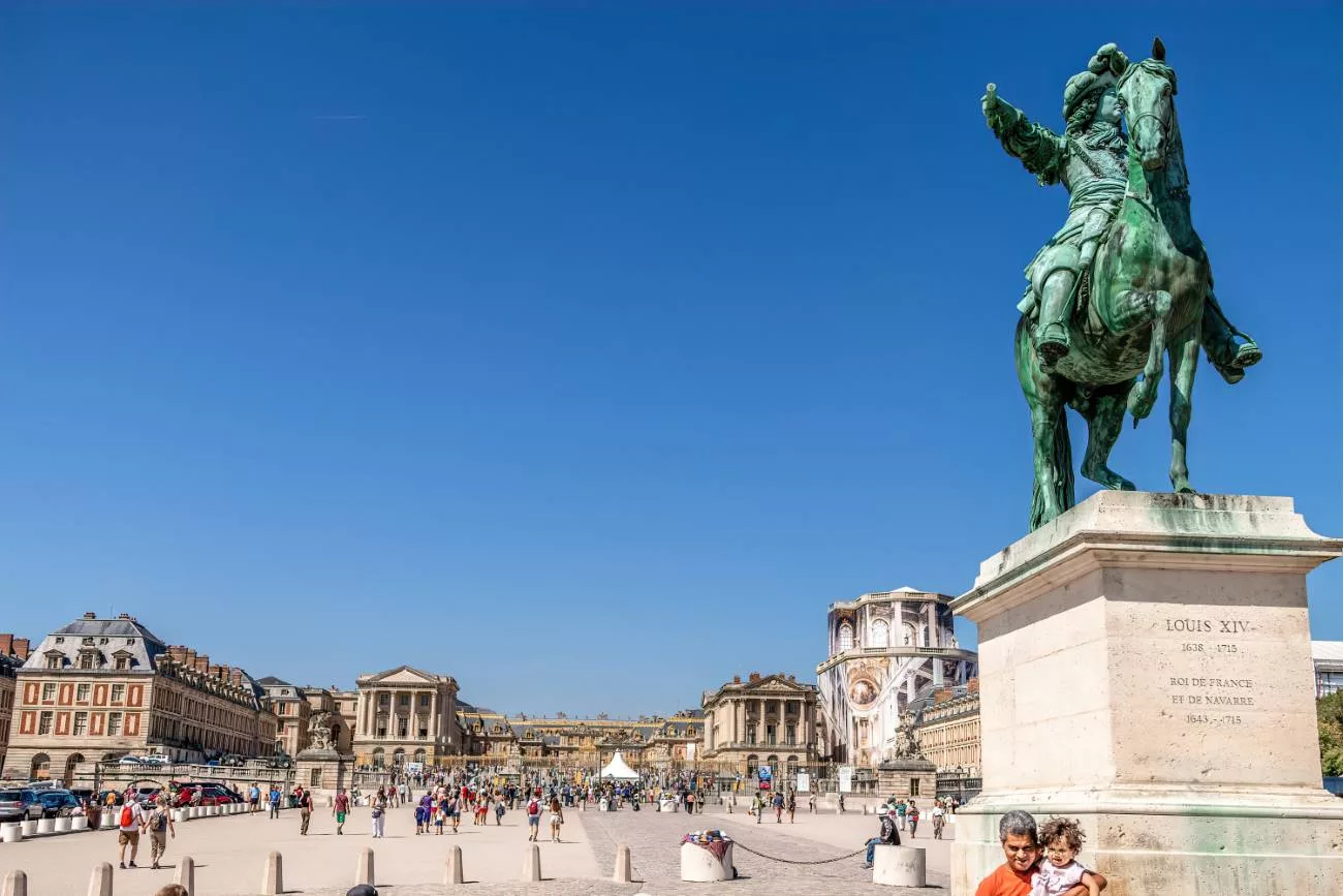 En marchant vers les grilles de Versailles, le roi Louis XIV trône sur un cheval de bronze