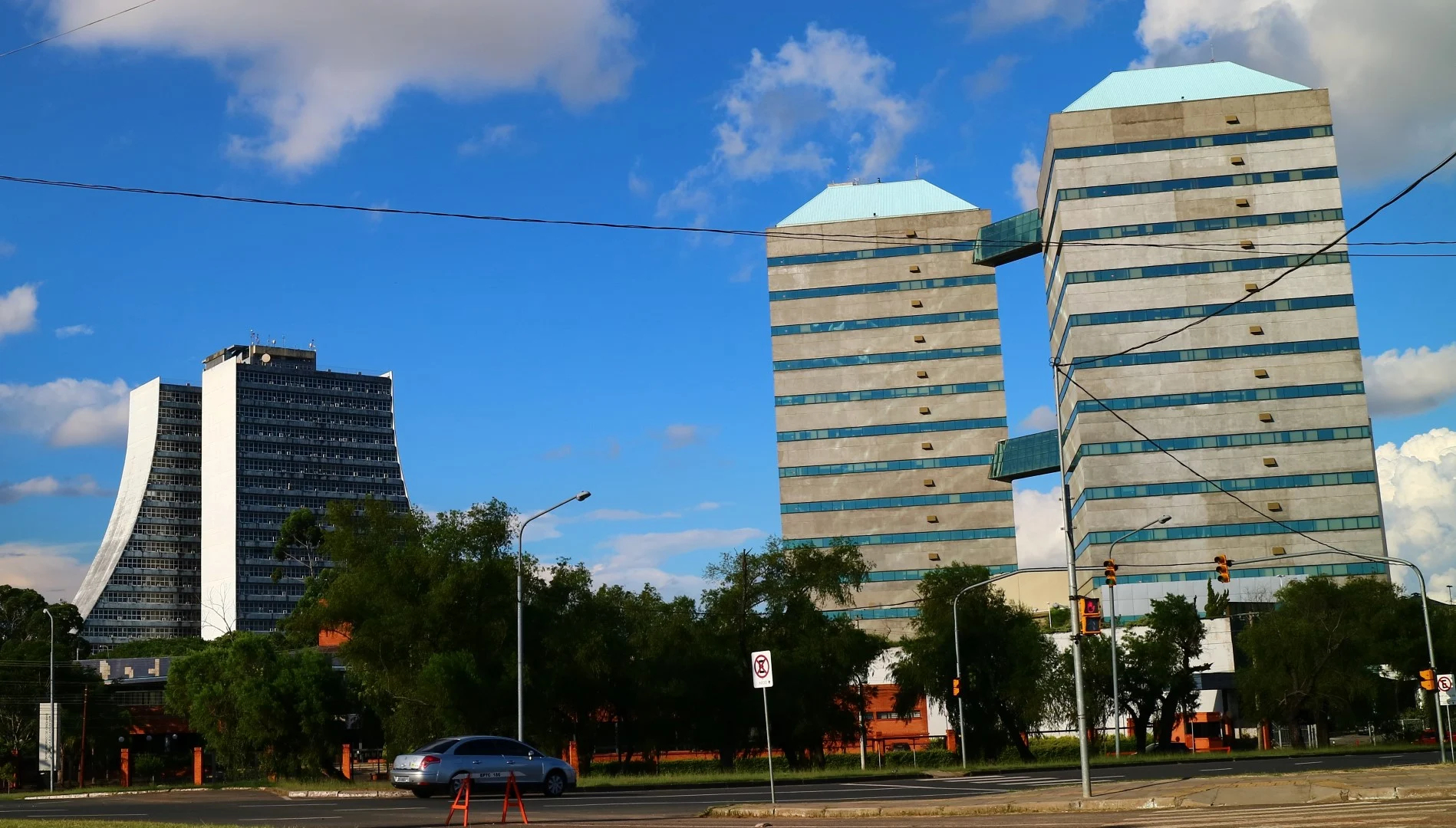 A wider view of the whole CAFF complex: the slanted boomerang slab and the two towers, all in raw concrete.